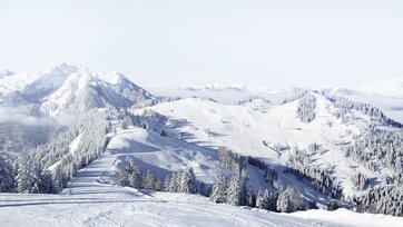 Schneereiche Pistenlandschaft mit Blick auf die umliegenden schneebedeckten Berge mit strahlend blauem Himmel | © Snow Space Salzburg