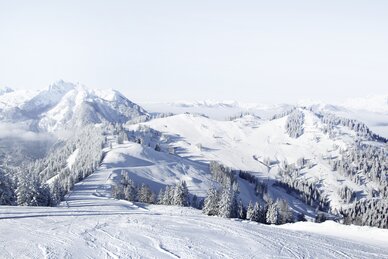 Snow-covered piste landscape with views of the surrounding snow-capped mountains and a bright blue sky | © Snow Space Salzburg