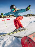 A girl skis over an action obstacle.