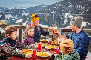 Parents sit with their four children on the terrace of an inn and eat lunch.