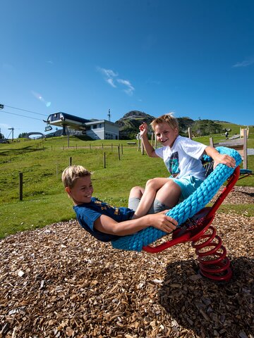 Zwei Kinder schaukeln auf Seilspielgerät bei der Gamskogelbahn Zauchensee im Sommer. | © Zauchensee Liftgesellschaft
