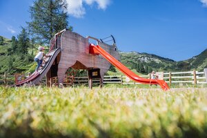 Girl climbs ramp of a cow-shaped play structure with red slide at the children’s playground in Zauchensee. | © Zauchensee Liftgesellschaft