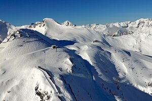 Panoramic view from Gamskogel with ski slopes, lifts and snowy mountains in background