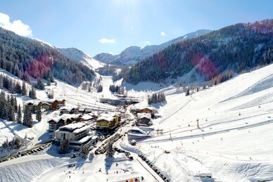 Zauchensee valley station with slopes, lifts, snowy mountains, skiers enjoying the sun