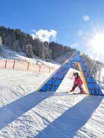 Child on skis passing colourful obstacle in Kinderland Zauchensee in sunshine