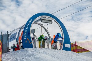 Two young skiers start simultaneously from Skimovie gate in Zauchensee