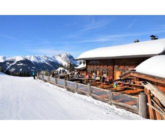 Terrace of a ski hut located directly on the piste and with a view of a snow-covered mountain range