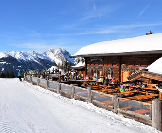 Terrasse einer Skihütte direkt an der Piste gelegen und mir Blick auf eine schneebedeckte Bergkette