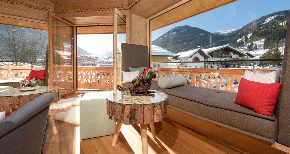 Bright relaxation room with wooden ceiling, loungers, cushions and mountain view