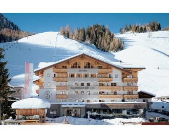 Hotel Salzburger Hof with wooden facade in front of snowy slope and ski lift | © Nadia Jabli