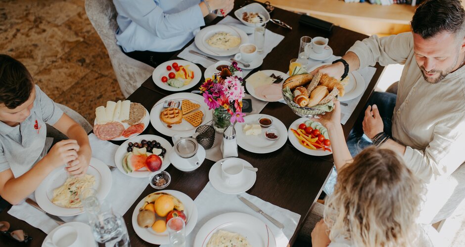 Four people having breakfast with bread, fruit, cold cuts, omelette and waffles | © Nadia Jabli