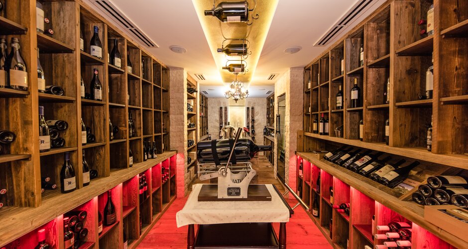 Wooden shelves with wine bottles and magnums in stylishly lit wine cellar | © Nadia Jabli