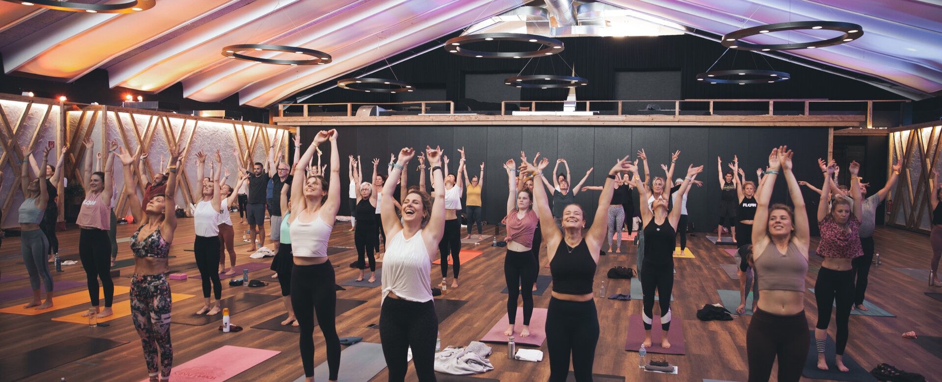 Viele Teilnehmer strecken ihre Hände während einer Yoga-Pose in die Höhe