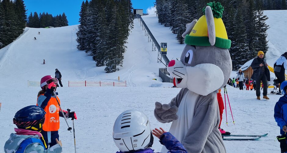 Das Maskottchen Hopsi gibt einem Kind ein High-Five | © Planai