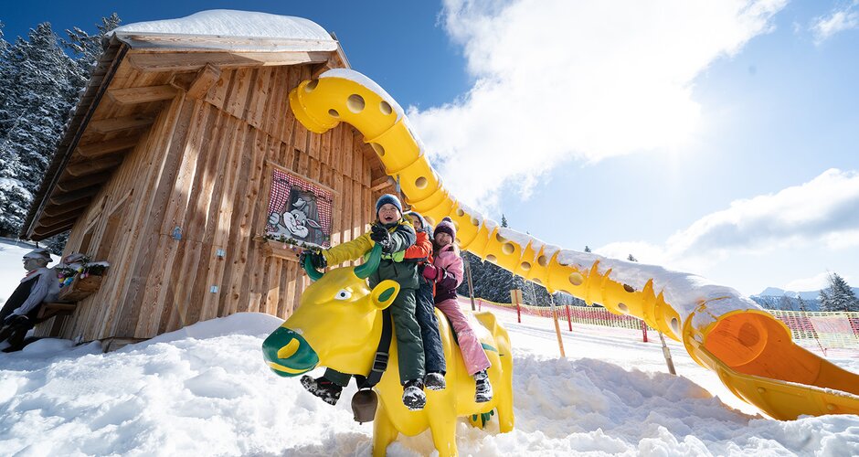 3 children sit on a yellow-green cow and laugh | © Josh Absenger