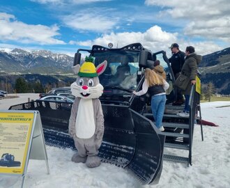 Das Maskottchen Hopsi steht vor dem Pistengerät während ein paar Leute es sich ansehen | © Dagmar Neureiter