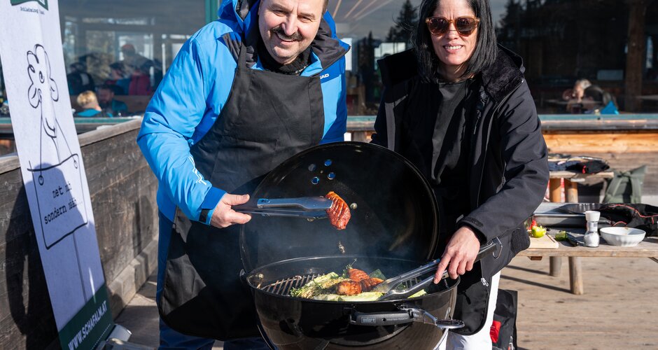 Johann Lafer und eine Frau grillen gemeinsam an einem Kugelgrill auf der Schaf-Alm. | © Mario Egger