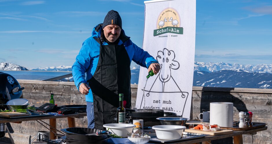 Johann Lafer grillt im Freien auf der Planai vor verschneiten Alpenbergen | © Mario Egger