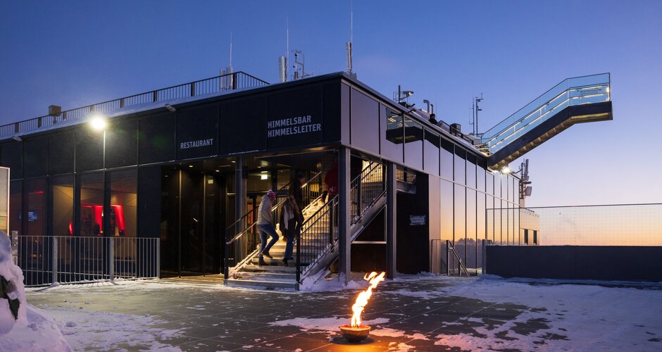 Modern building on Dachstein with flame and skywalk at sunset surrounded by snow | © Martin Huber