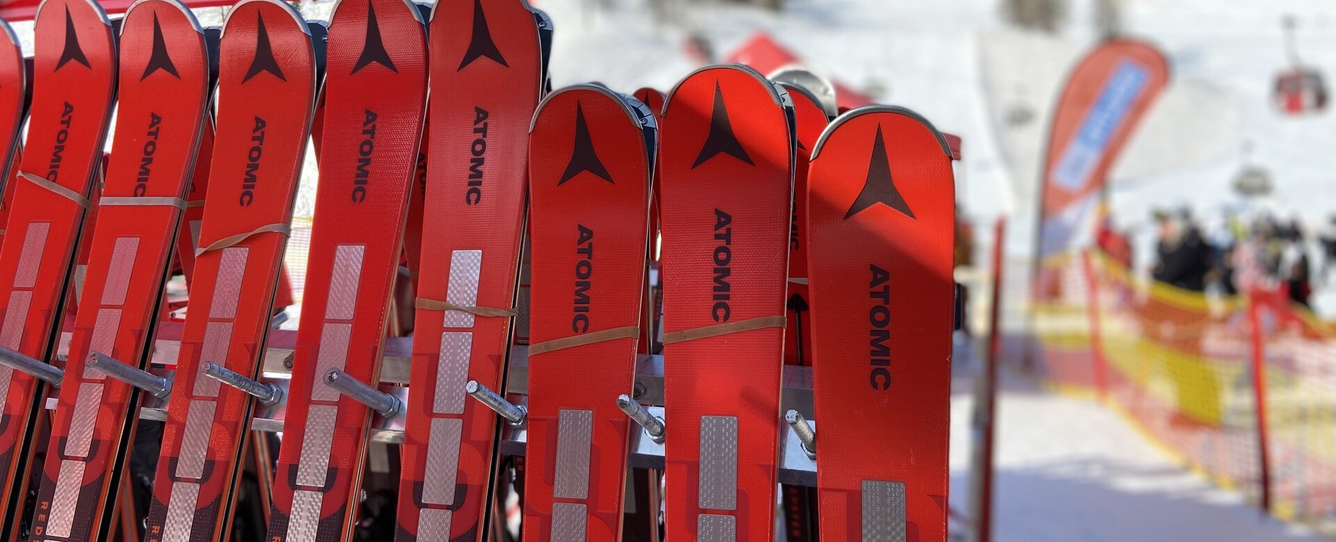 Red Atomic ski pairs leaning against a ski rack