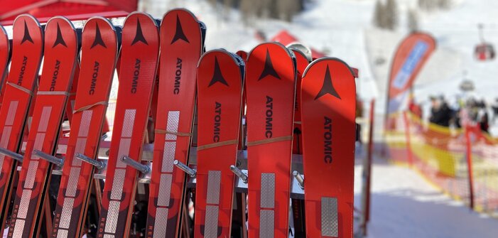 Red Atomic ski pairs leaning against a ski rack