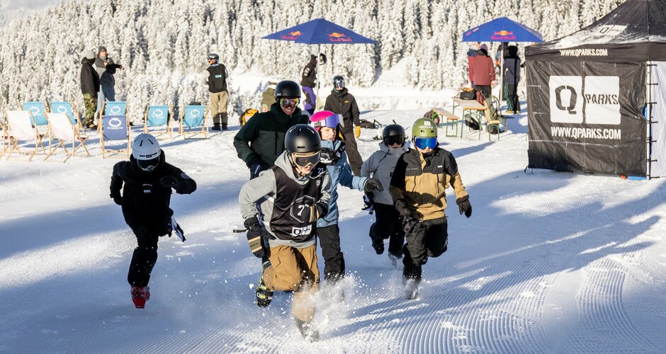 Sechs Kinder laufen in Skibekleidung über den Schnee Richtung Kamera und im Hintergrund sind Liegestühle und Sonnenschirme sowie ein paar Personen zu sehen | © Hannes Mautner