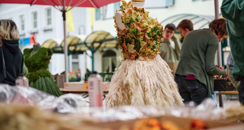 Mannequin in a dress made of colorful autumn leaves and ornamental grass during a creative workshop at Herbst.Königin | © Matthias Fritzenwallner