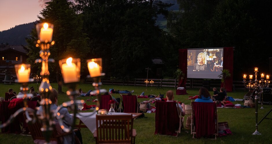 Besucher beim Open-Air-Kino Licht.Spiele auf Liegestühlen, im Vordergrund brennende Kerzenleuchter auf Tischen | © Matthias Fritzenwallner