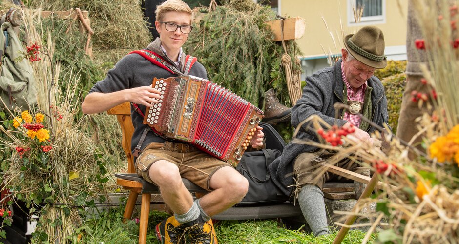 Young man in lederhosen playing accordion on a decorated wagon during the harvest festival parade in Bad Hofgastein | © Gasteinertal Tourismus GmbH