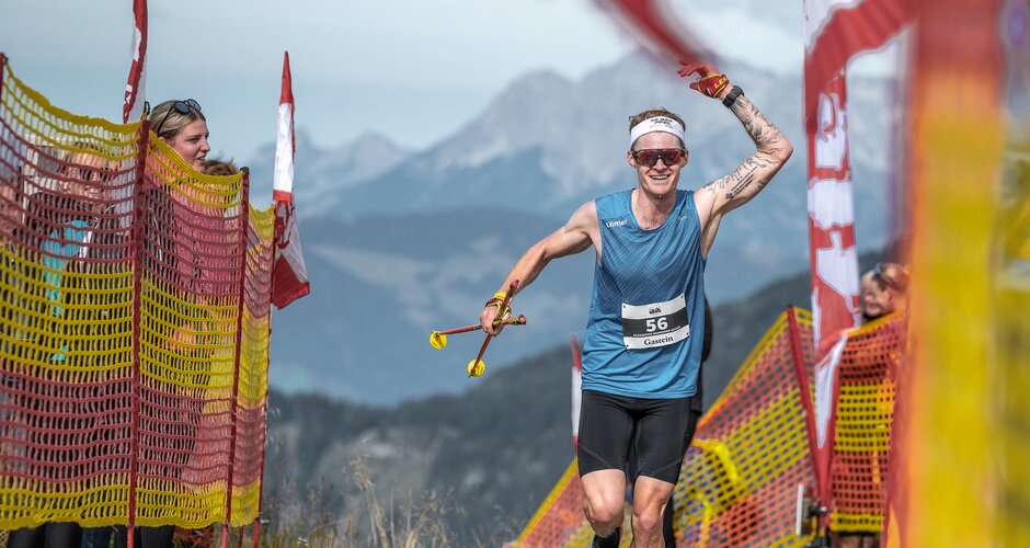 Runner number 56 celebrates finishing the Beinhoat race between red-yellow safety nets on a mountain summit. | © Beinhoat