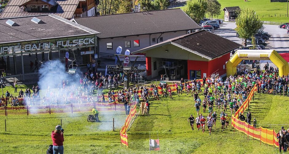 Runners start a steep mountain race in sunshine in front of the Gipfelbahn Fulseck valley station. | © Beinhoat