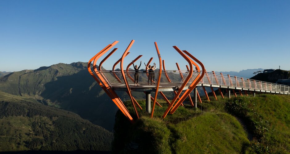 Three ladies are standing on a viewing platform with their hands outstretched towards the sky | © Gasteinertal Tourismus GmbH, Marktl Photography