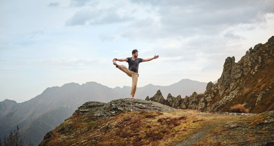 Man standing in a yoga pose on a rock | © Gasteinertal Tourismus GmbH, Michael Königshofer