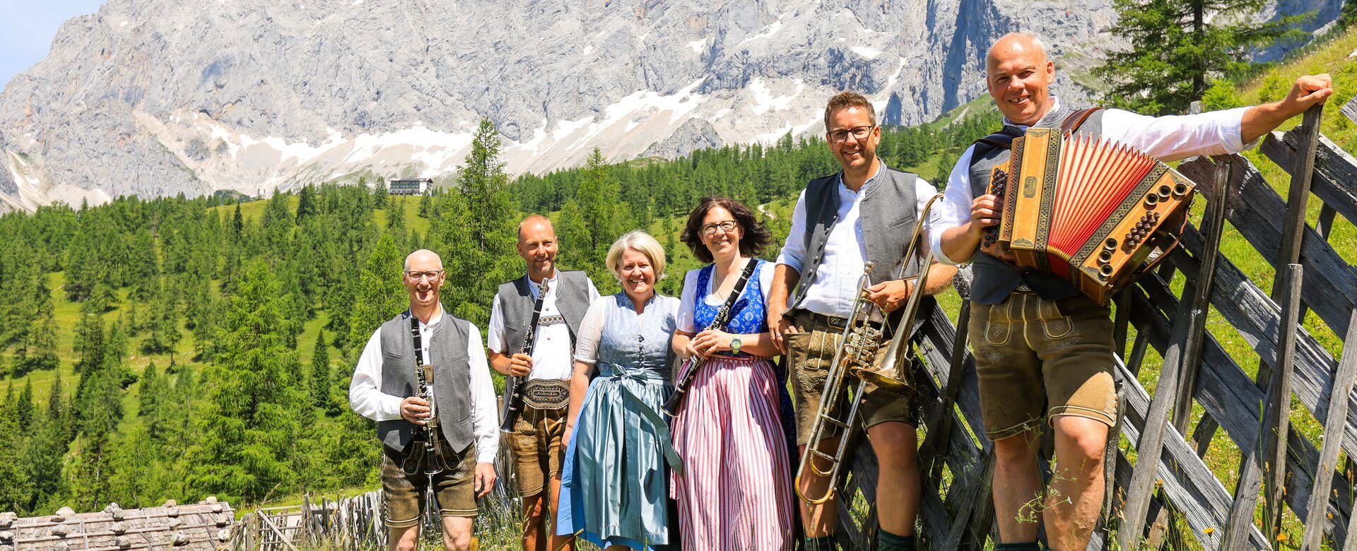 Volksmusikgruppe in Tracht mit Instrumenten beim Ramsauer Almtag, stehend auf Almwiese mit Blick auf das Dachsteinmassiv | © Michael Simonlehner