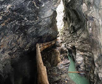 Wooden walkway through narrow rocky gorge with green water in Liechtensteinklamm, light from above | © JOSalzburg