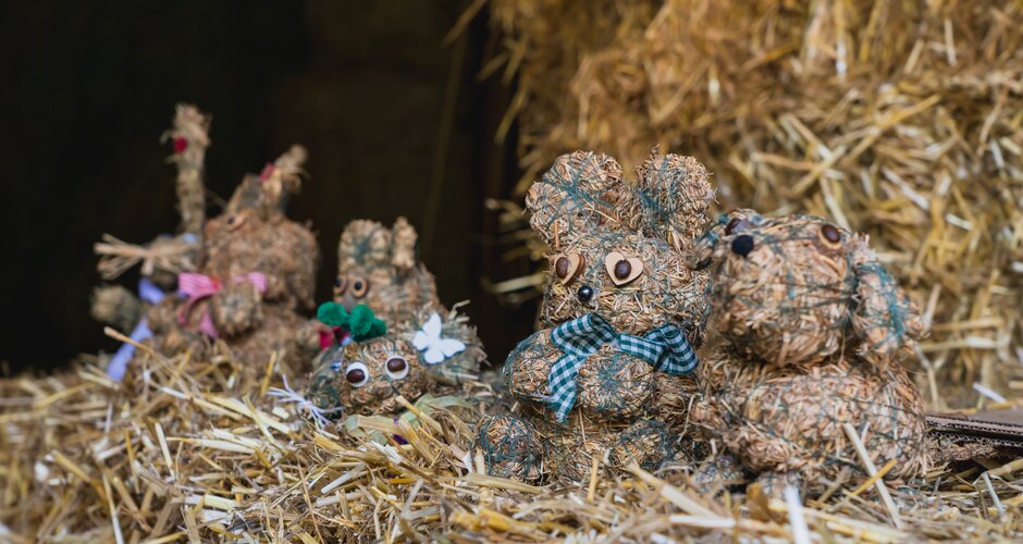 Several hay animal figures sit on straw bales, decorated with bows and button eyes. | © Lukas Anzinger