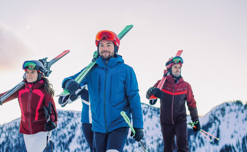 Four skiers carrying their skis on their shoulders – the perfect start for the Back2Ski course, a program for returning skiers. | © Ski amadé