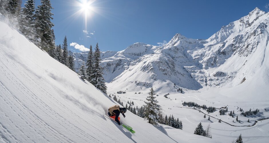 Skifahrer beim Freeriden im freien Gelände mit sonnenbestrahlten beschneiten Bergen im Hintergrund | © Gasteinertal Tourismus GmbH | Christoph Oberschneider