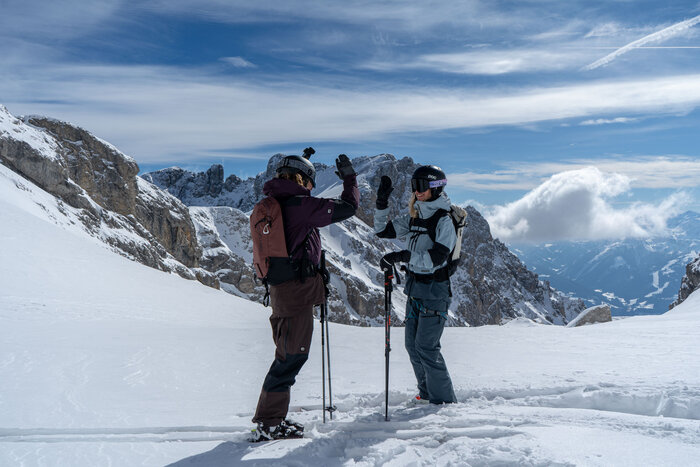 Two skiers high-five each other in the snow on Dachstein Glacier slope | © Josh Absenger