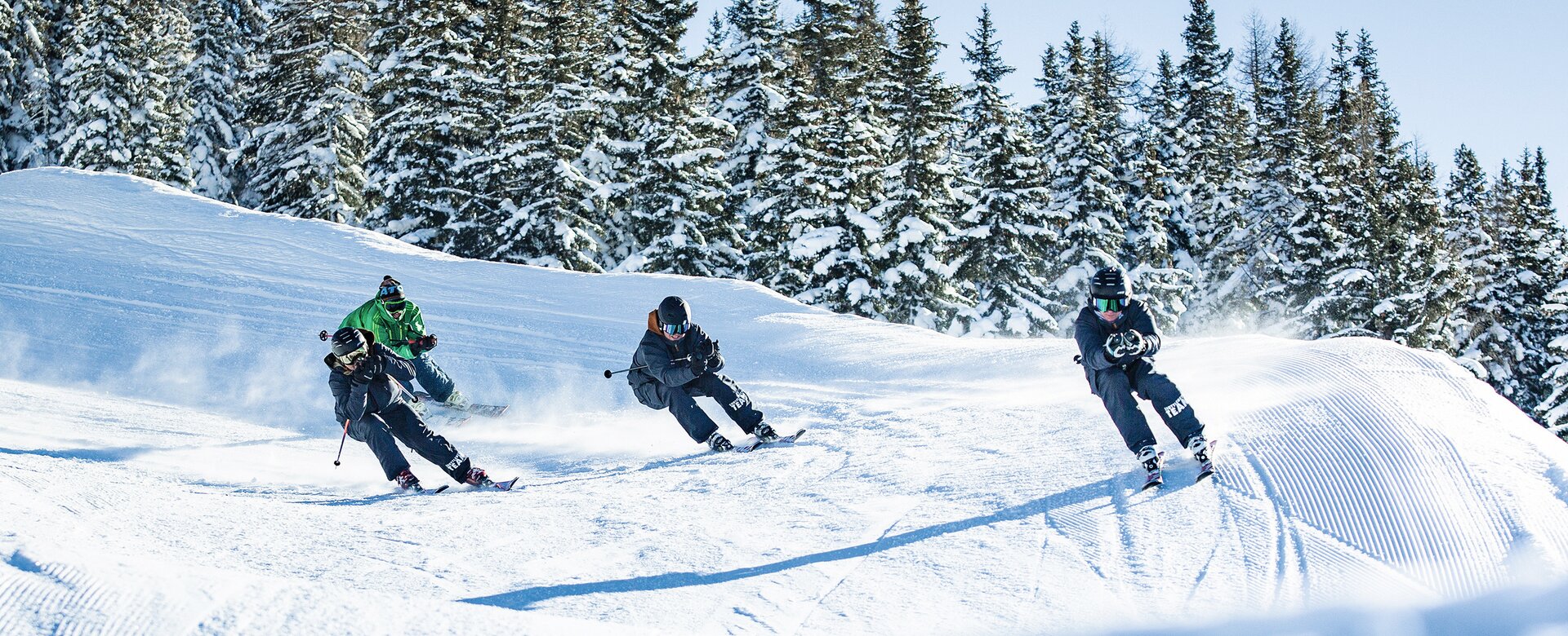 Four young skiers with helmets racing dynamically on snowy Funcross course at Shuttleberg resort | © Shuttleberg