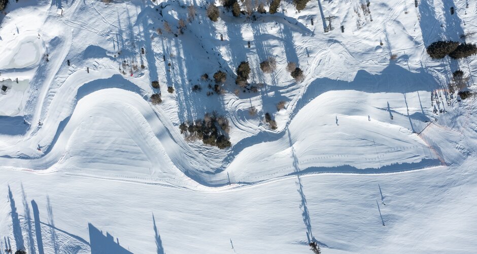 Aerial view of snowy Funcross course with curves, trees and skiers in Shuttleberg ski terrain | © Shuttleberg