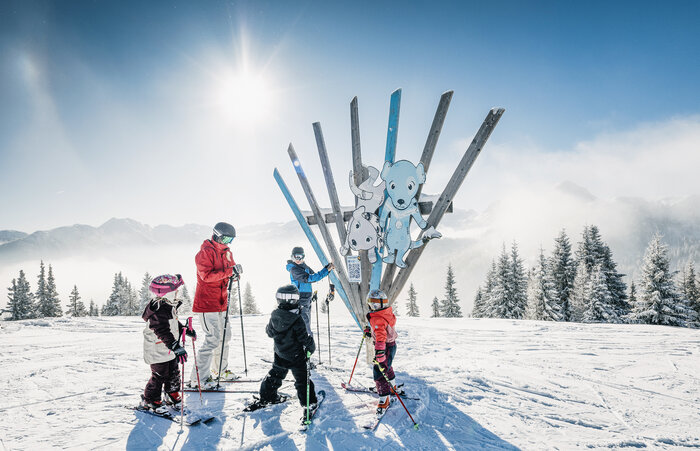 Kinder mit Begleitperson auf Skiern vor Holzskulptur mit Tierfiguren am Family Run im Shuttleberg | © Shuttleberg