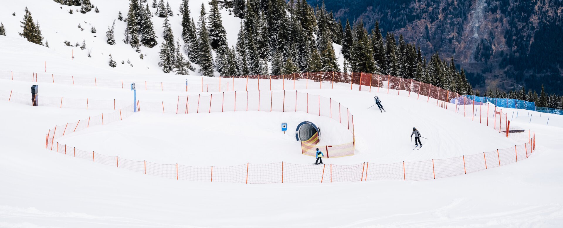 Skiers on the Funline with snow tunnel and curves in a snowy alpine mountain setting | © Christian Riefenberg | QParks
