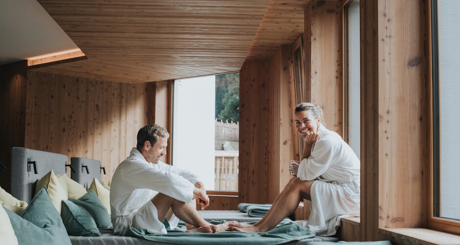 Couple in bathrobes relaxing in wooden spa lounge at Hotel Tauernhof