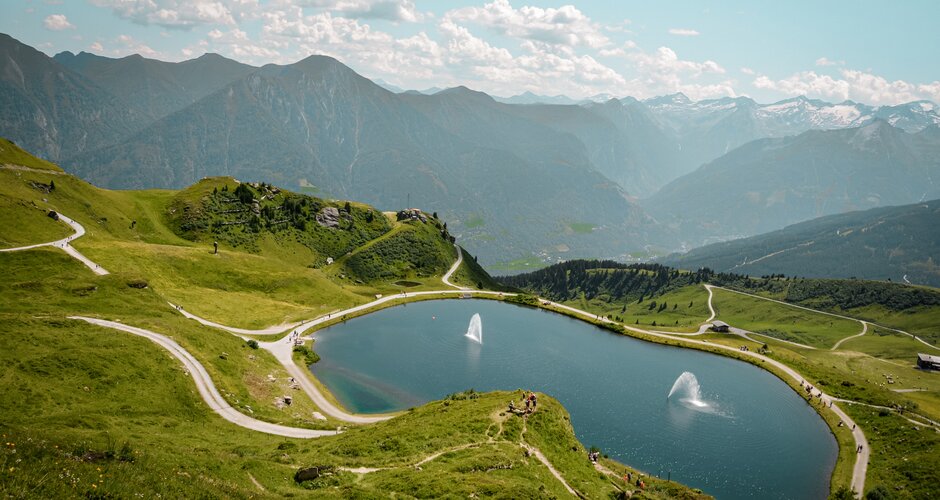 Speichersee auf der Schlossalm mit Wasserfontänen, umgeben von Wanderwegen und Almlandschaft in Gastein | © Gasteiner Bergbahnen AG