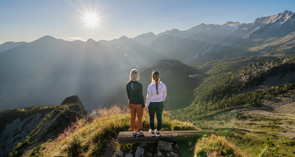 Zwei Frauen genießen bei Sonnenaufgang die Aussicht vom Graukogel auf das Gasteinertal und die umliegenden Berge | © Skigastein, seven frames