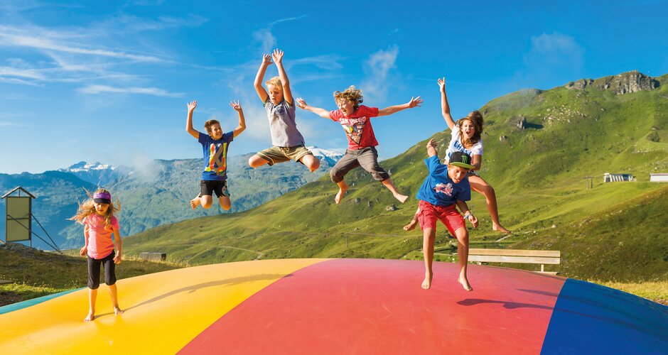 Kids jumping on colorful pillow at Schlossalm playground with mountain view and summer vibes | © Gasteiner Bergbahnen AG, Wolkersdorfer