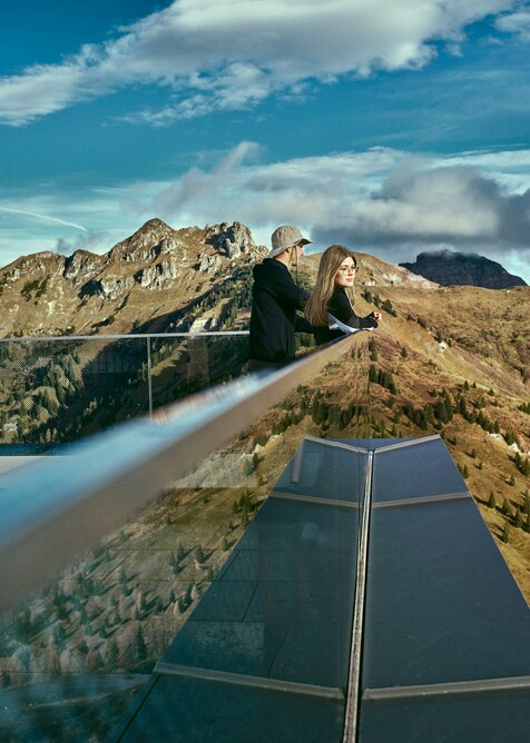 Two people enjoying the alpine view from the modern lookout at Kieserl in Großarl, surrounded by autumn-colored mountains. | © Großarler Bergbahnen