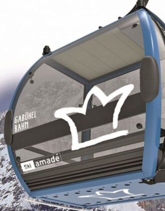 Blue-black Gabühel gondola with Hochkönig logo in front of snowy rock face in Ski amadé region | © Hochkönig Bergbahnen