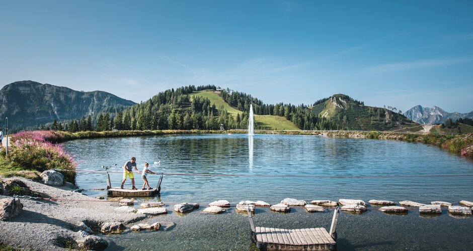 A father and his daughter stand on a raft and pull themselves to the opposite shore by a rope | © Christian Schartner